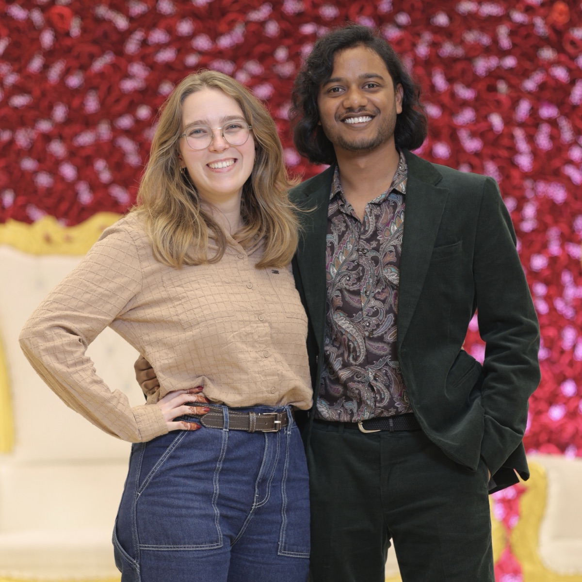 Saurav en Cecillia, lachend voor een wand van rode bloemen